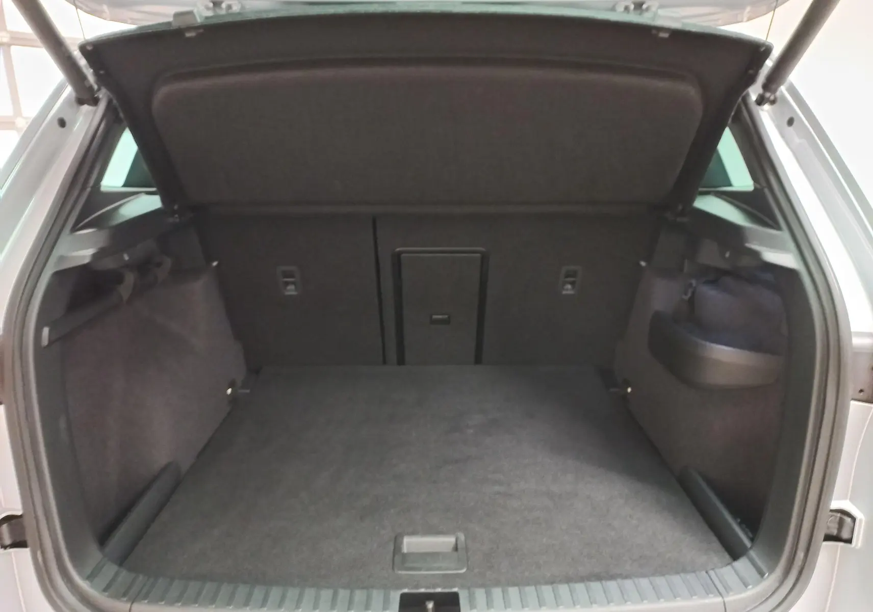 Coffre ouvert du Skoda Karoq gris argent 2025, vue arrière montrant l'espace de chargement et la finition intérieure noire.