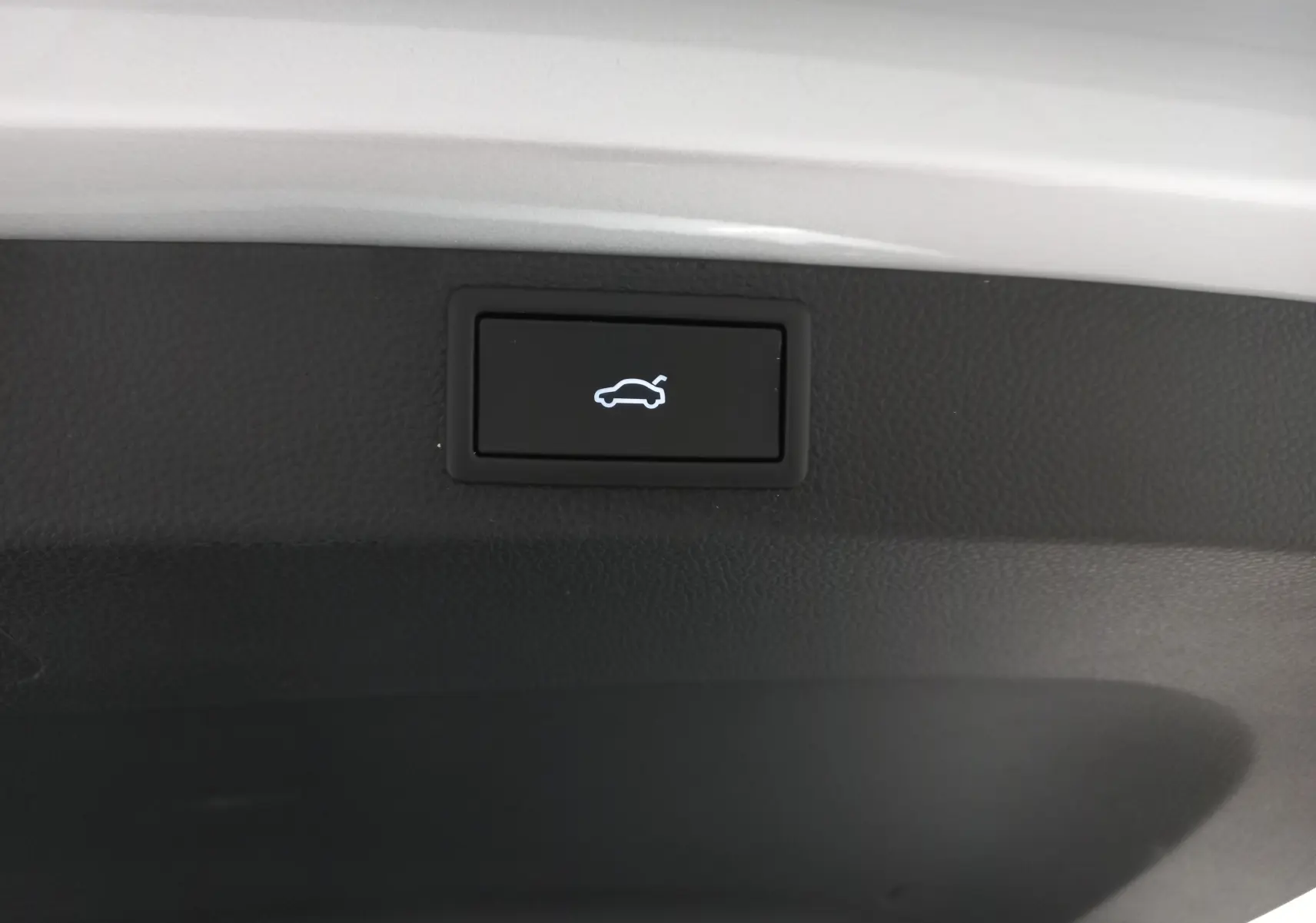 Bouton d'ouverture électrique du hayon sur le bord intérieur du coffre d'un Skoda Karoq gris argent 2025.