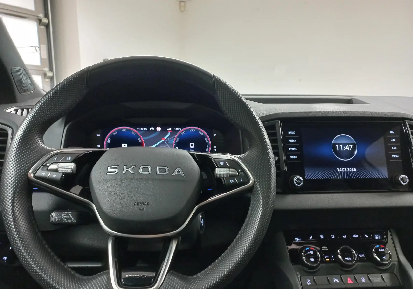 Vue intérieure centrée sur le volant SKODA et le tableau de bord numérique du Karoq gris argent 2025 Sportline.