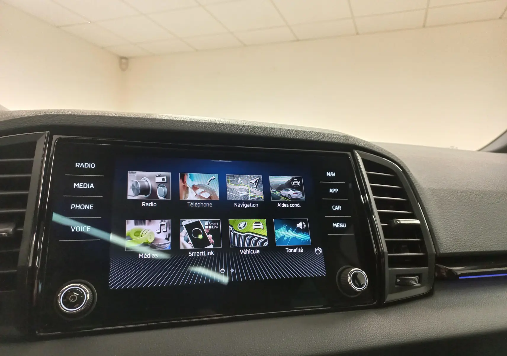 Écran tactile central du tableau de bord du Skoda Karoq gris argent, affichant le menu multimédia et navigation.