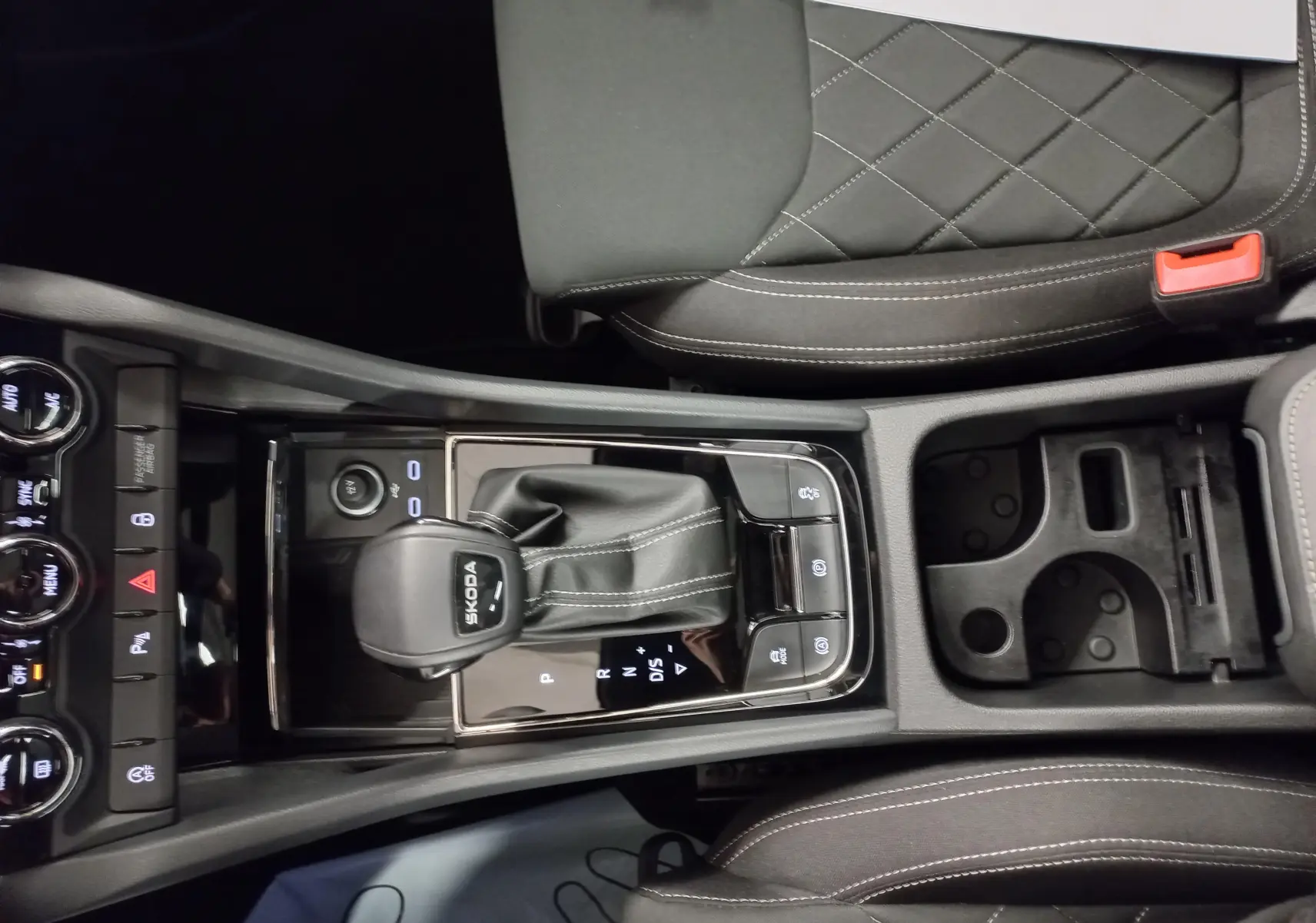 Vue plongeante sur la console centrale du Skoda Karoq 2025, avec levier de vitesse DSG7 et sellerie noire matelassée.