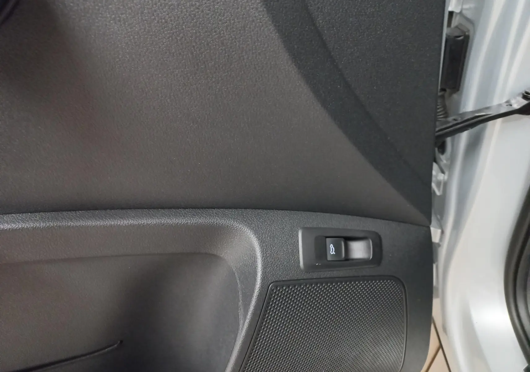 Détail de la commande d'ouverture électrique du hayon sur la porte intérieure d'un Skoda Karoq gris argent 2025.
