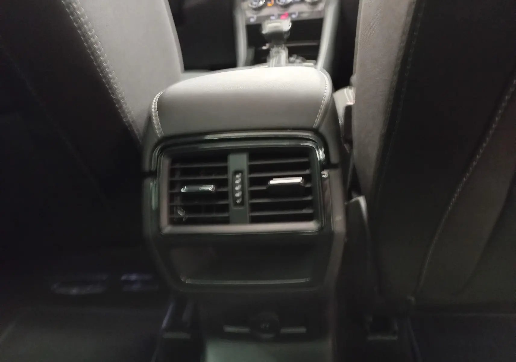 Vue rapprochée de la console centrale arrière du Skoda Karoq 2025, avec aérateurs noirs et sellerie sombre.