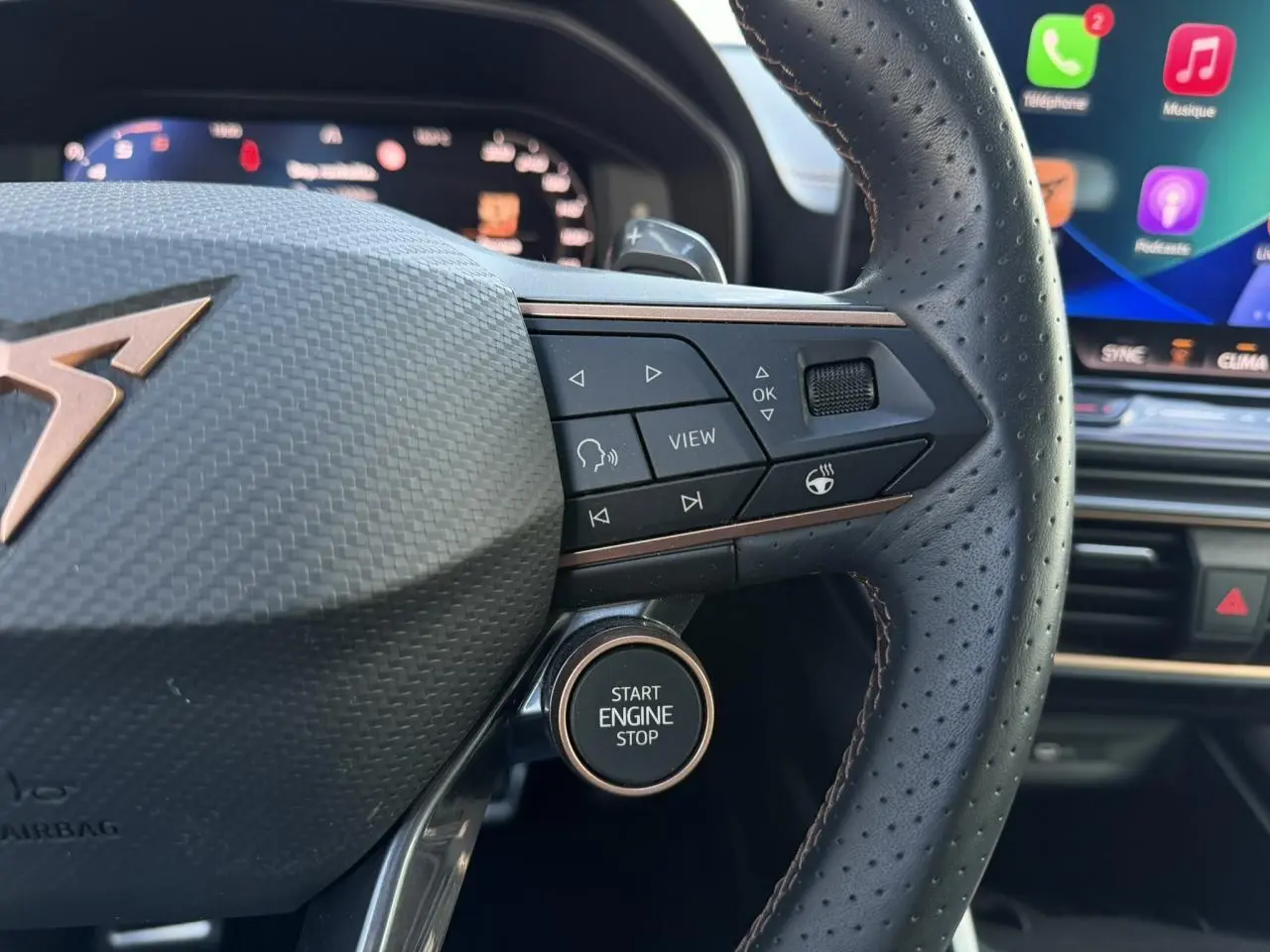 Gros plan sur le volant cuir perforé du CUPRA Formentor bleu Fjord, avec boutons multifonctions et bouton Start Engine Stop.