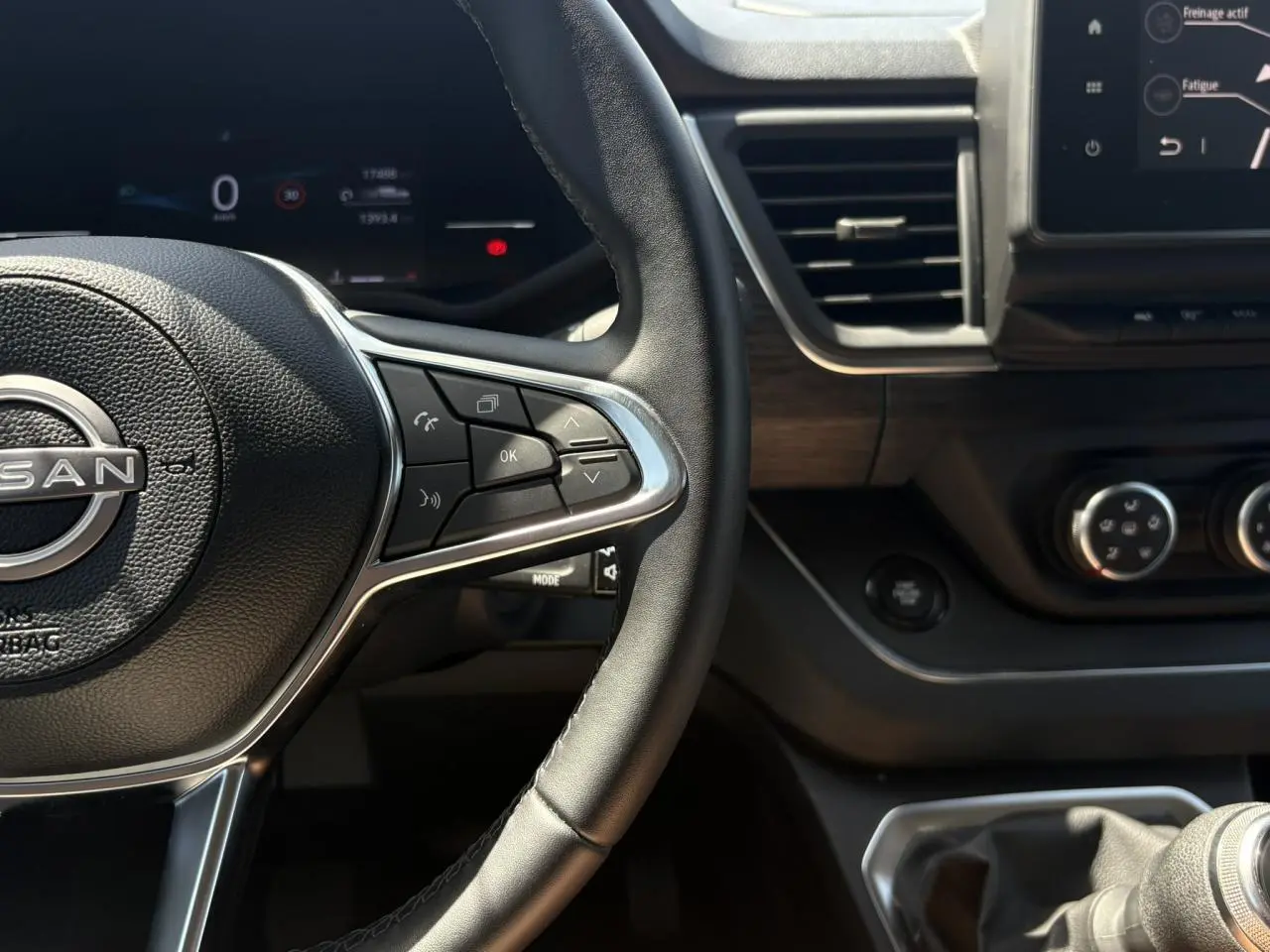 Vue rapprochée du volant et tableau de bord du Nissan Primastar Combi noir, avec commandes au volant et écran tactile visible.
