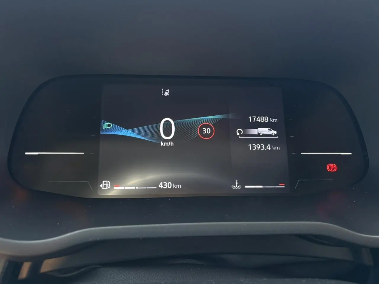 Tableau de bord numérique du Nissan Primastar Combi 2025 affichant vitesse, autonomie et alertes, vue frontale rapprochée.