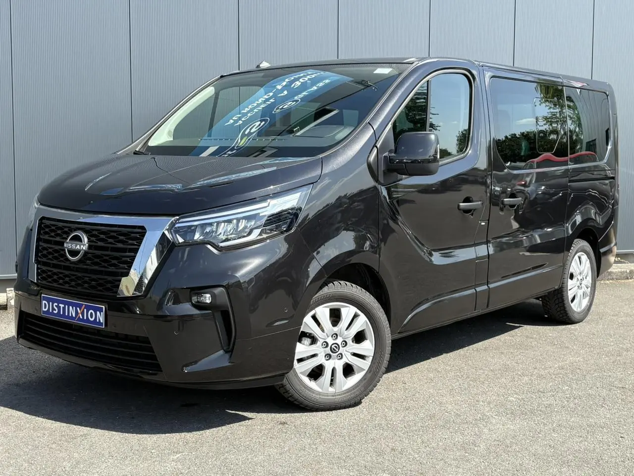 Nissan Primastar Combi noir Minuit en 3/4 avant droit, hayon vitré et vitres arrière surteintées visibles.