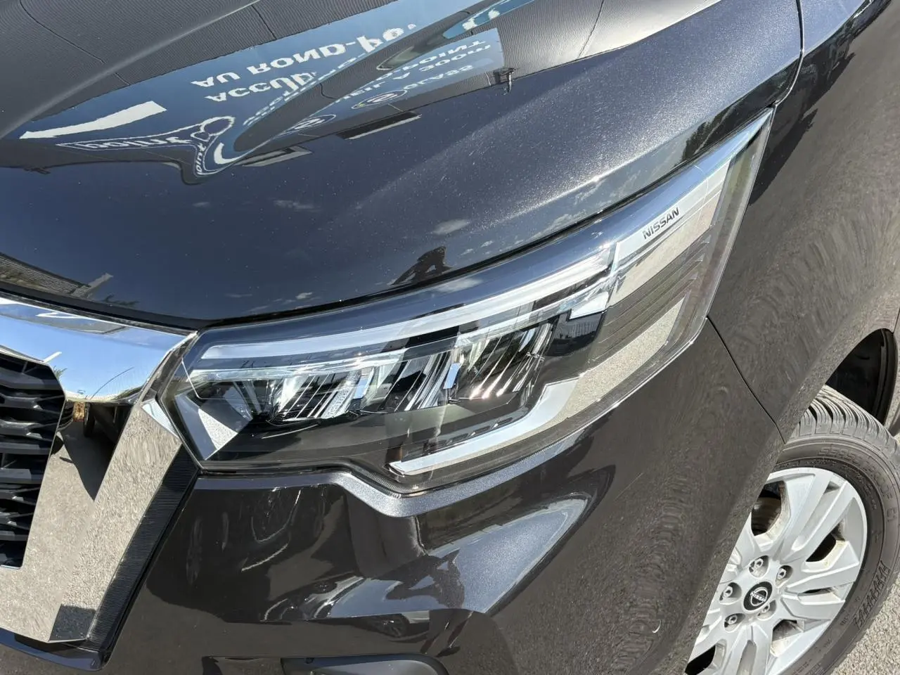 Gros plan sur le phare avant droit noir minuit du Nissan Primastar Combi 2025 avec jante alliage visible.