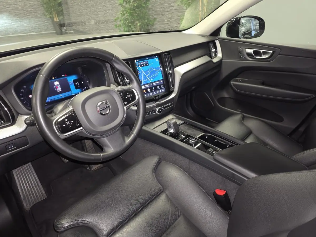 Intérieur noir cuir du Volvo XC60 2023 vu côté conducteur, avec tableau de bord digital et écran tactile central.