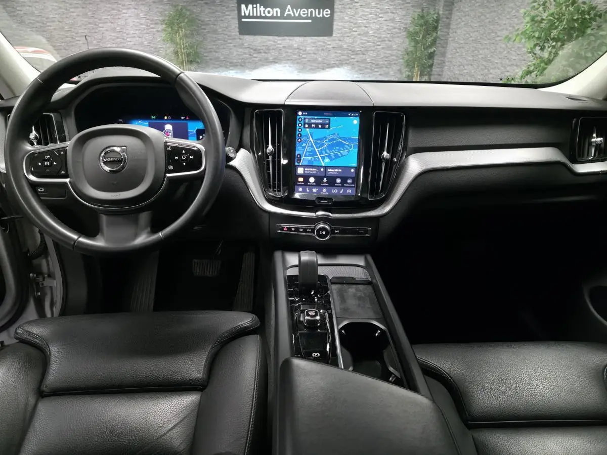 Vue intérieure avant du Volvo XC60 gris, avec tableau de bord digital et écran tactile central lumineux.