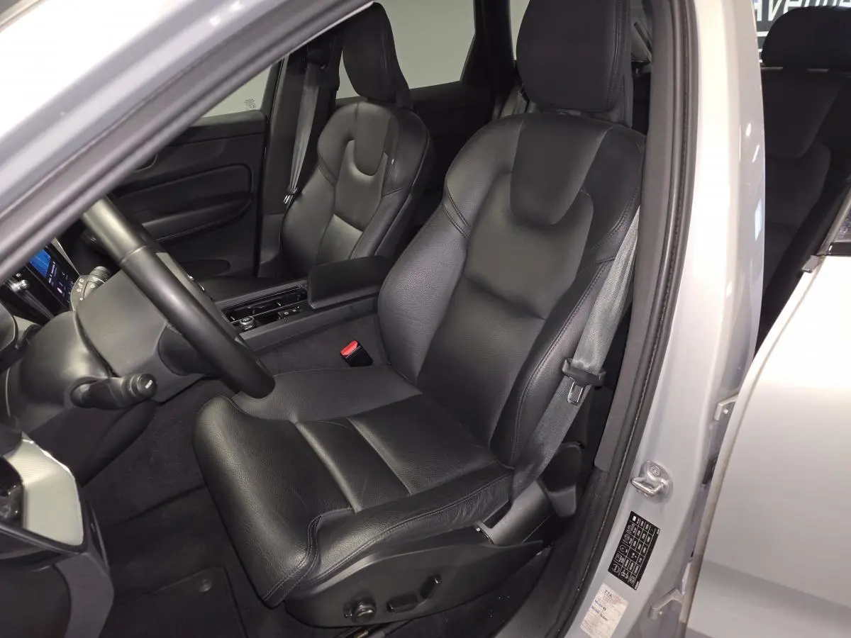 Vue intérieure côté conducteur du Volvo XC60 gris 2023, siège en cuir noir avec accoudoir central.