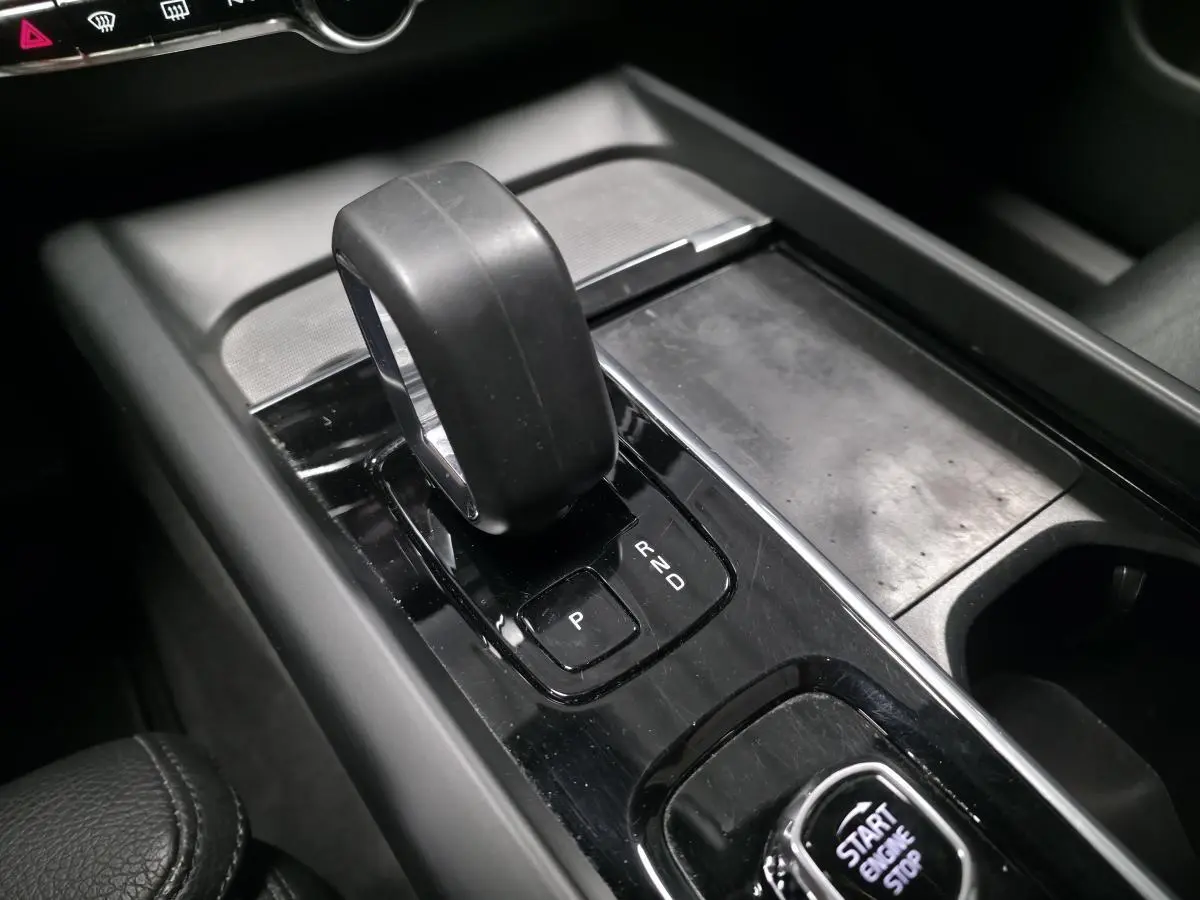 Gros plan sur la console centrale noire avec levier de vitesses automatique et bouton Start/Stop du Volvo XC60 gris.