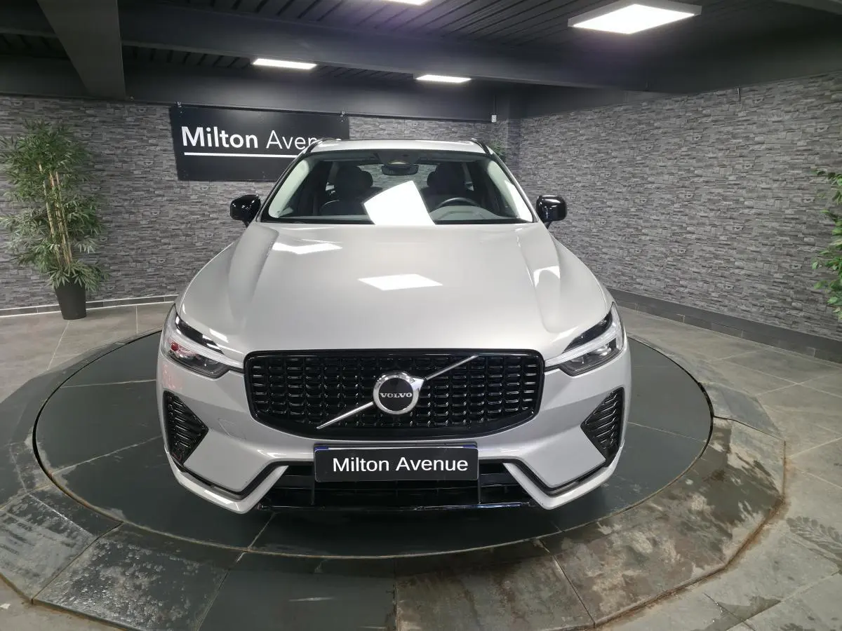 Vue avant d'un Volvo XC60 gris métallisé avec calandre noire laquée et détails noirs sur pare-chocs dans un showroom.