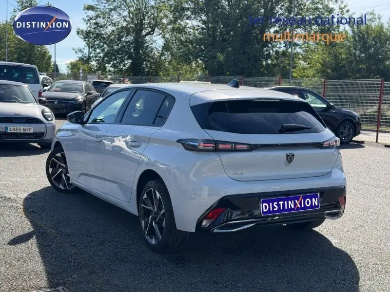 Vue 3/4 arrière droite d'une Peugeot 308 blanche Okénite avec feux arrière LED et jantes alliage noires.