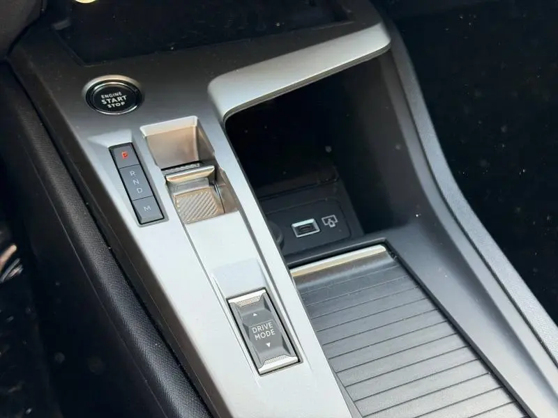 Vue rapprochée de la console centrale grise avec levier de boîte auto et bouton start du Peugeot 308 Hybrid 2025.