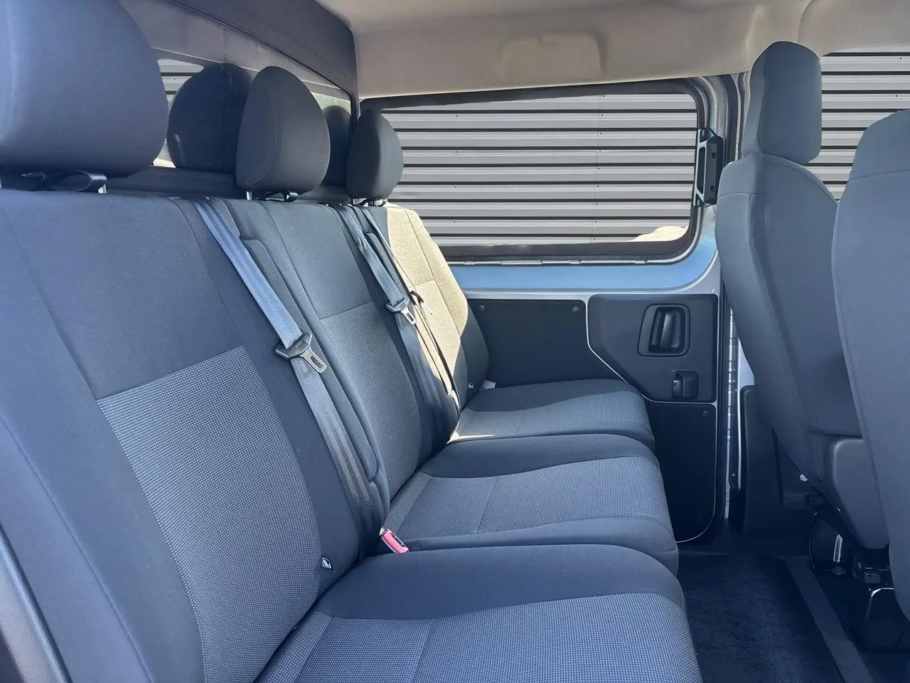 Vue intérieure côté droit sur la banquette arrière grise du Citroën Jumpy 2026 avec fenêtre latérale coulissante.