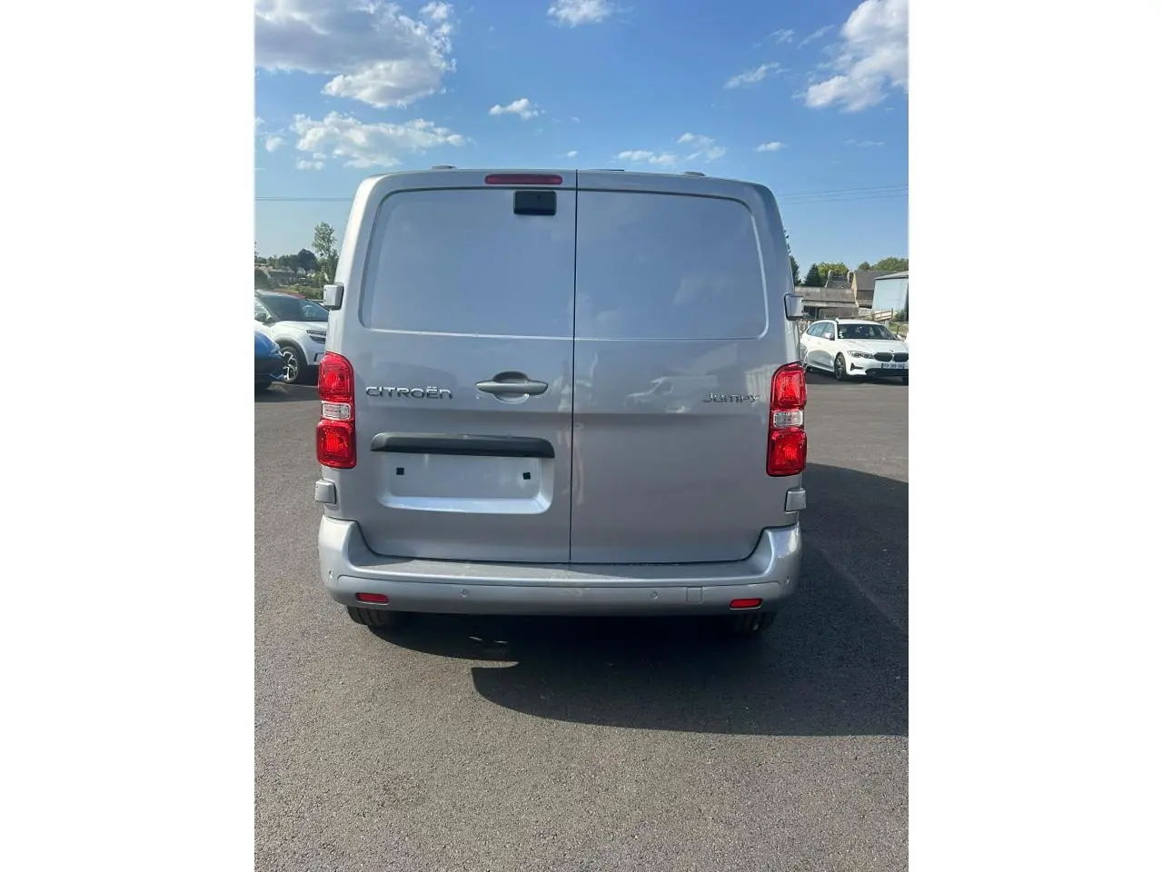 Vue arrière d'un Citroën Jumpy gris Artense avec portes battantes et caméra de recul visible en haut.