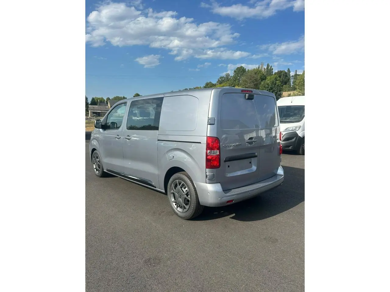 Vue 3/4 arrière droite d’un Citroën Jumpy gris Artense avec portes arrière battantes et jantes noires.
