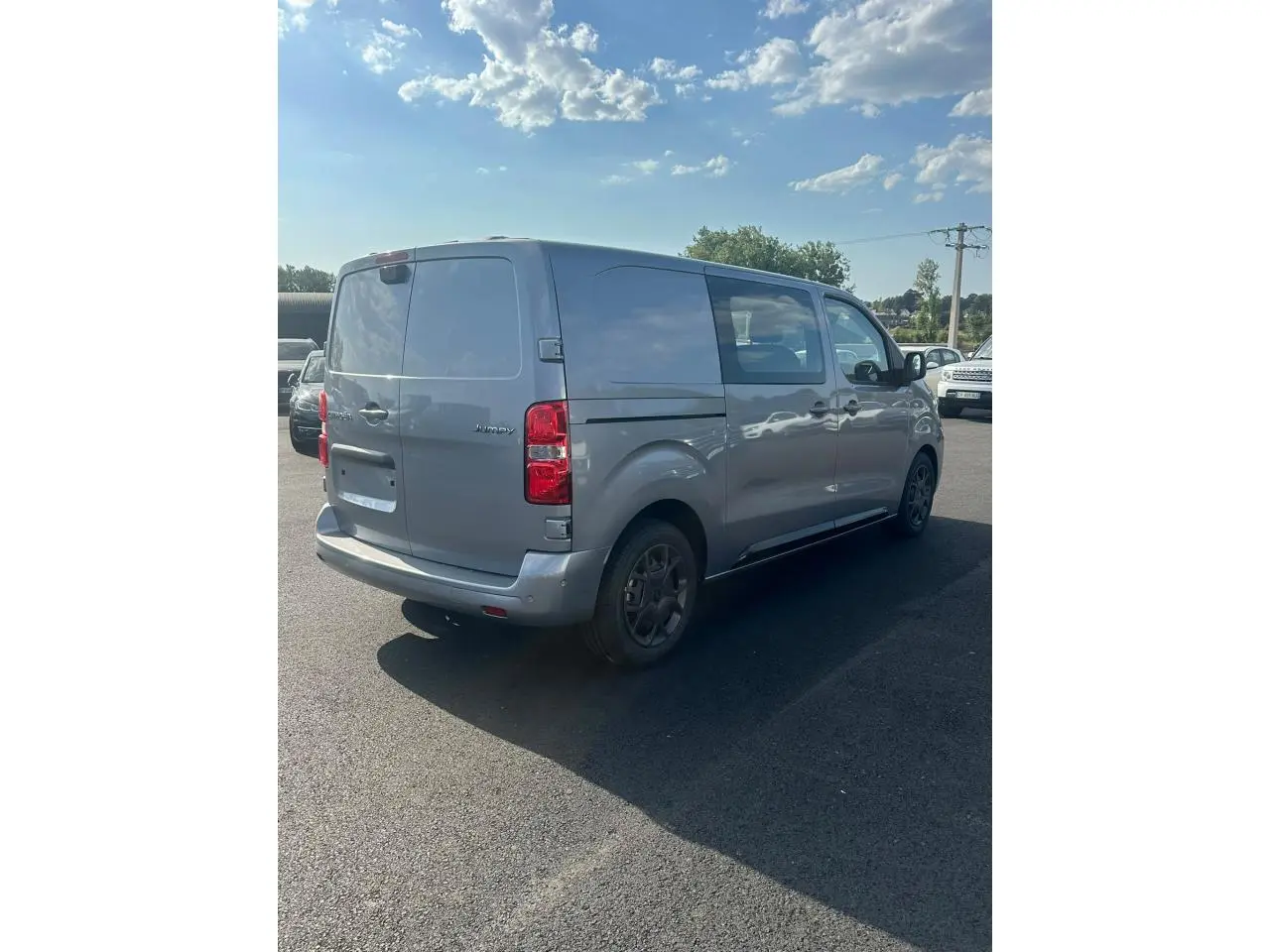 Vue 3/4 arrière droite du Citroën Jumpy gris Artense avec portes arrière battantes et jantes noires.