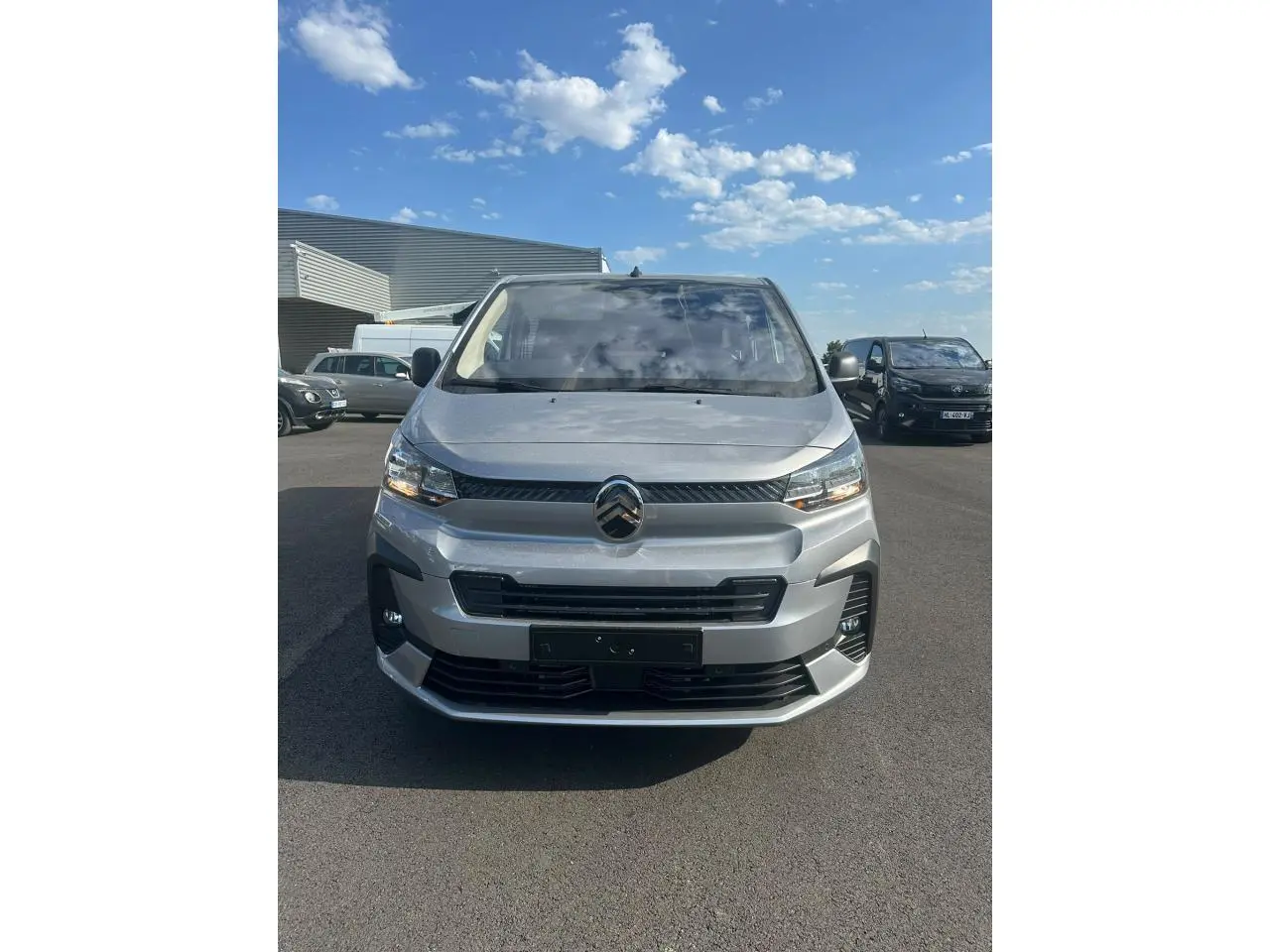 Vue avant d'un Citroën Jumpy gris Artense avec projecteurs antibrouillard et calandre noire sous un ciel bleu.