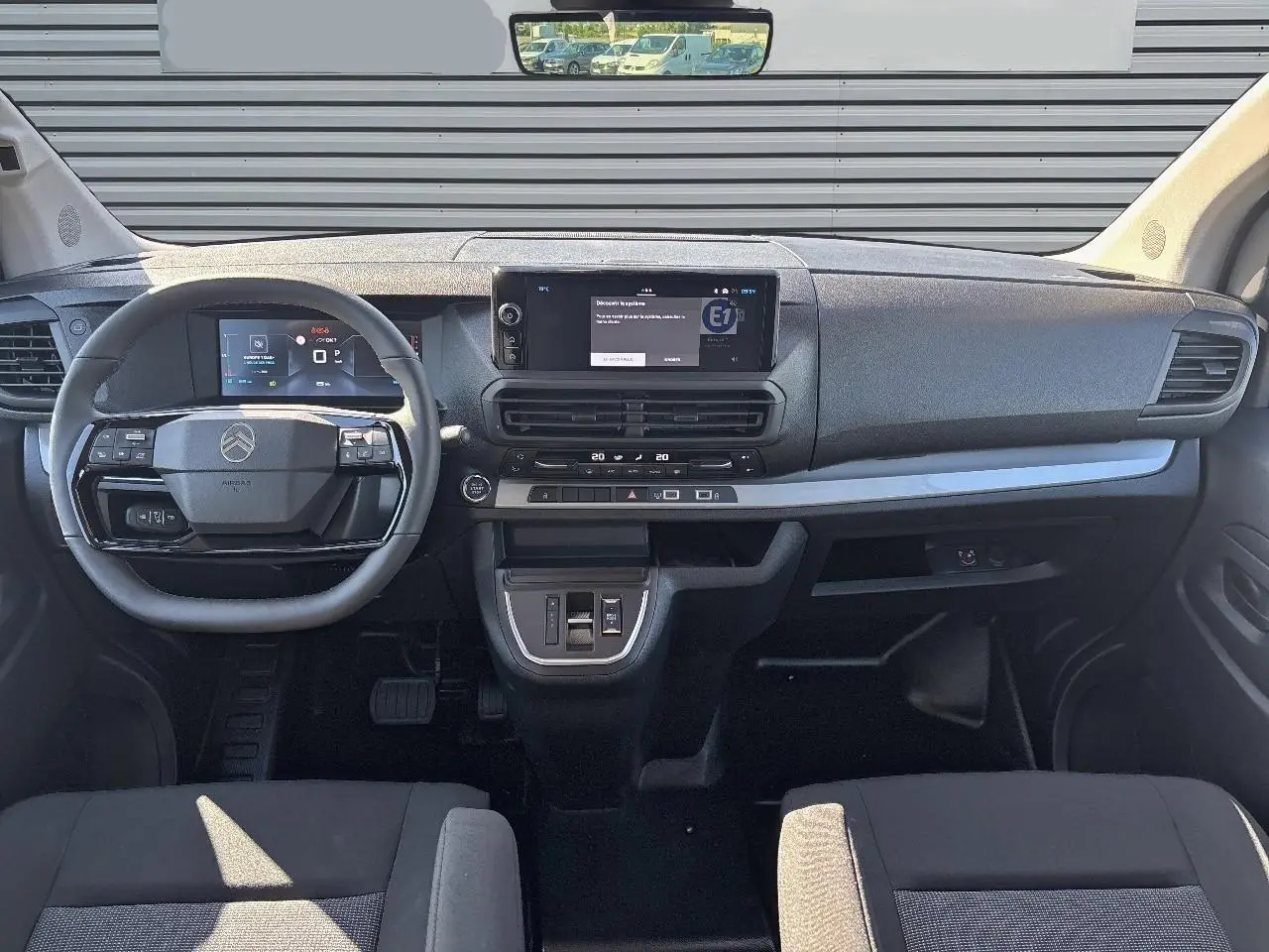 Vue intérieure frontale du tableau de bord du Citroën Jumpy gris Artense, avec volant cuir et écran tactile central.