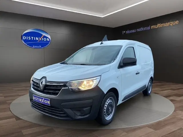 Renault Express Van blanc en 3/4 avant droit, avec boucliers noirs et phare avant allumé dans un showroom.