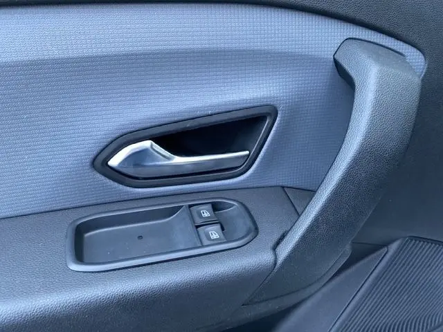 Gros plan sur la poignée de porte intérieure noire et les commandes de lève-vitres du Renault Express Van blanc 2023.