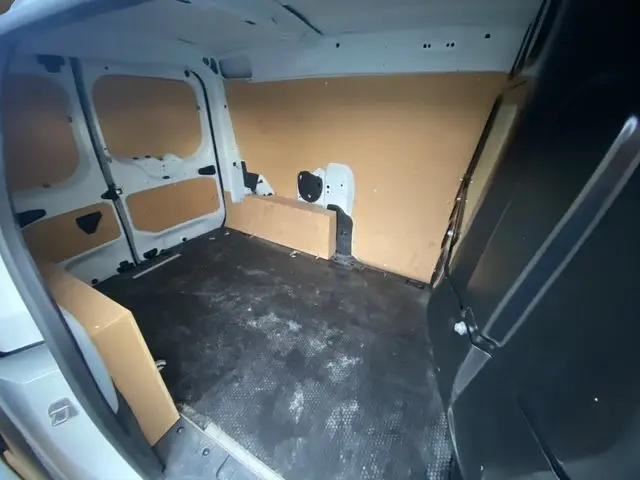 Intérieur du coffre du Renault Express Van blanc, vue de l'arrière droit avec habillage bois et cloison vitrée noire.
