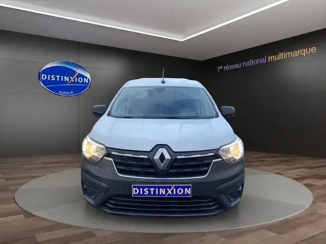 Vue frontale d'un Renault Express Van blanc avec calandre noire et phares allumés dans un showroom Distinxion.