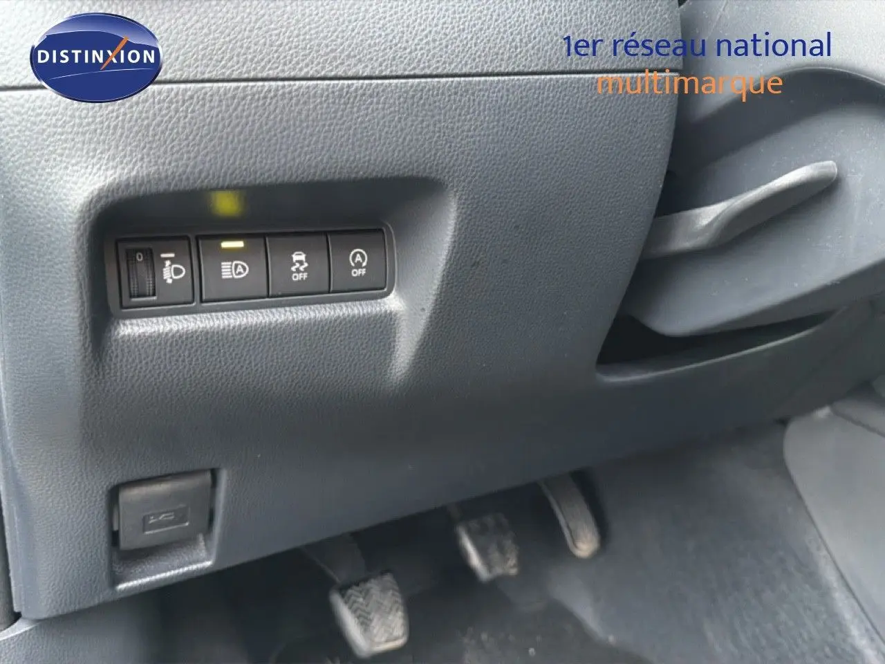 Vue intérieure sur les commandes de réglage des phares et aides à la conduite côté gauche d'une Toyota Aygo X noire 2025.