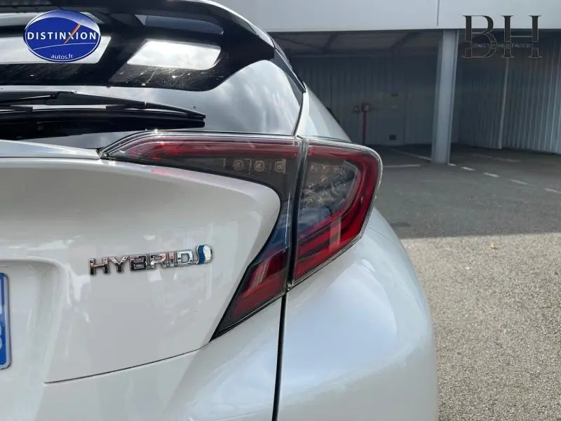 Gros plan sur l'arrière droit blanc nacré bi-ton du Toyota C-HR 122h Hybrid avec feu arrière LED et badge Hybrid.