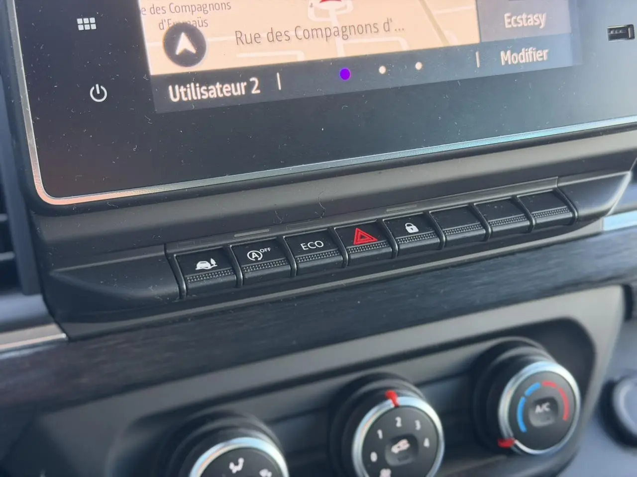 Gros plan sur la console centrale du Nissan Primastar gris, montrant les boutons de commande et l'écran tactile.
