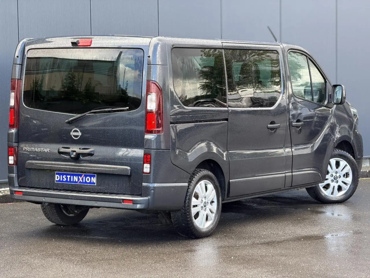 Vue 3/4 arrière droite d'un Nissan Primastar gris Comète avec hayon vitré et jantes alliage 17 pouces.
