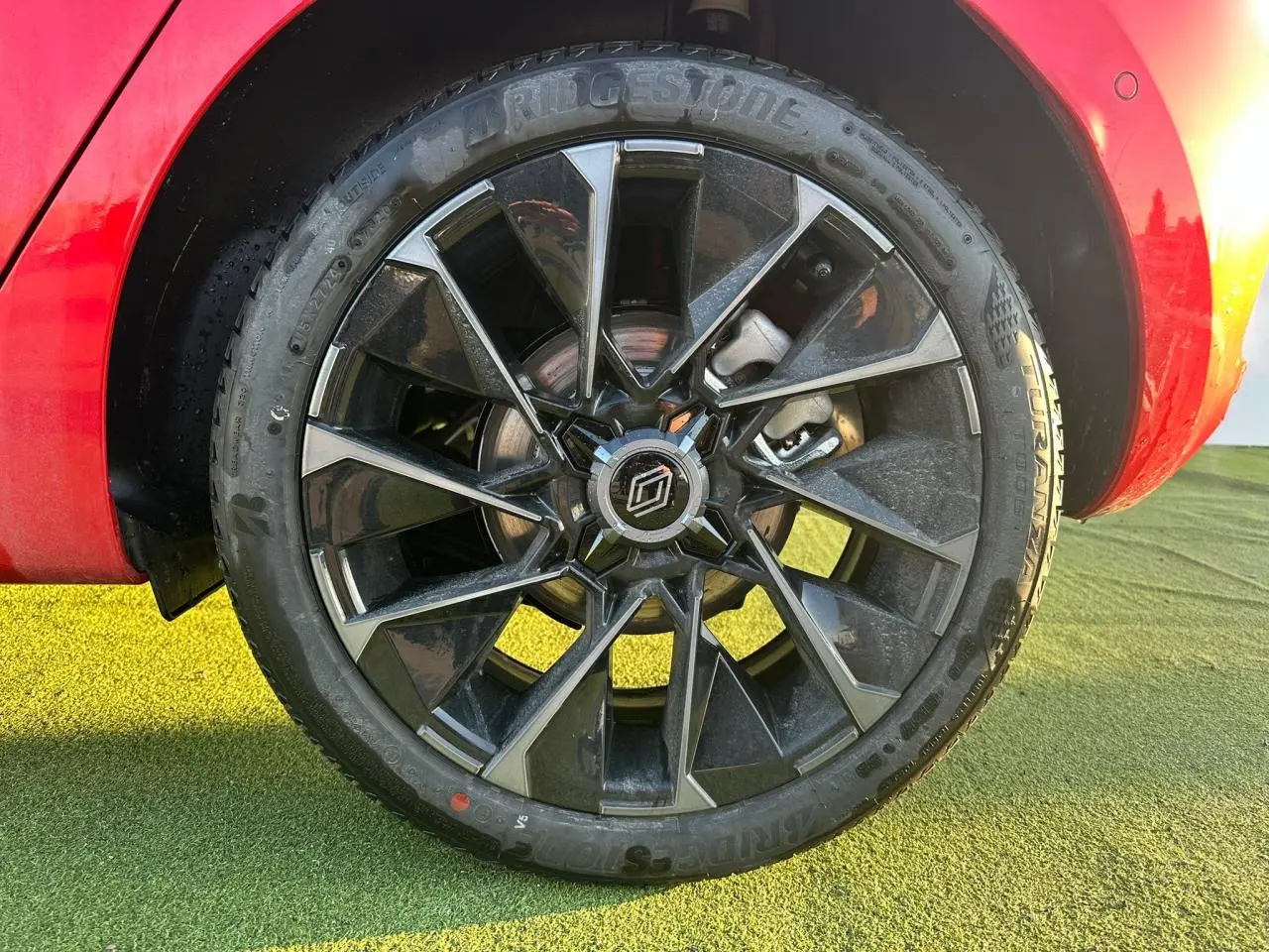 Gros plan sur la jante alliage 17 pouces noire et grise de la Renault Clio V rouge foncé, avec partie arrière visible.