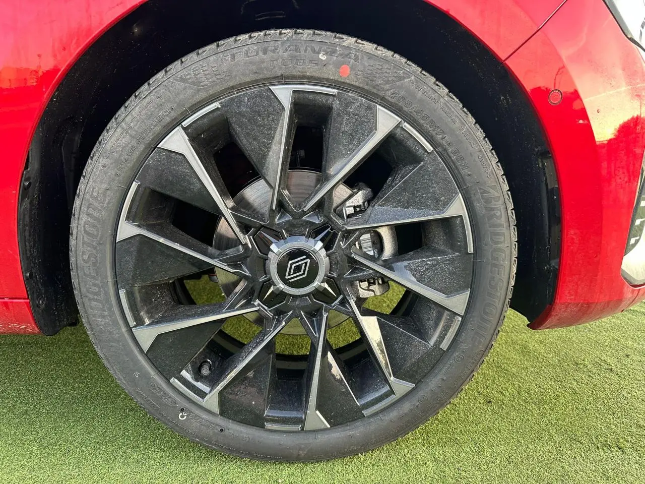 Gros plan sur la jante alliage noire et grise de la Renault Clio rouge foncé, avec logo Alpine au centre.