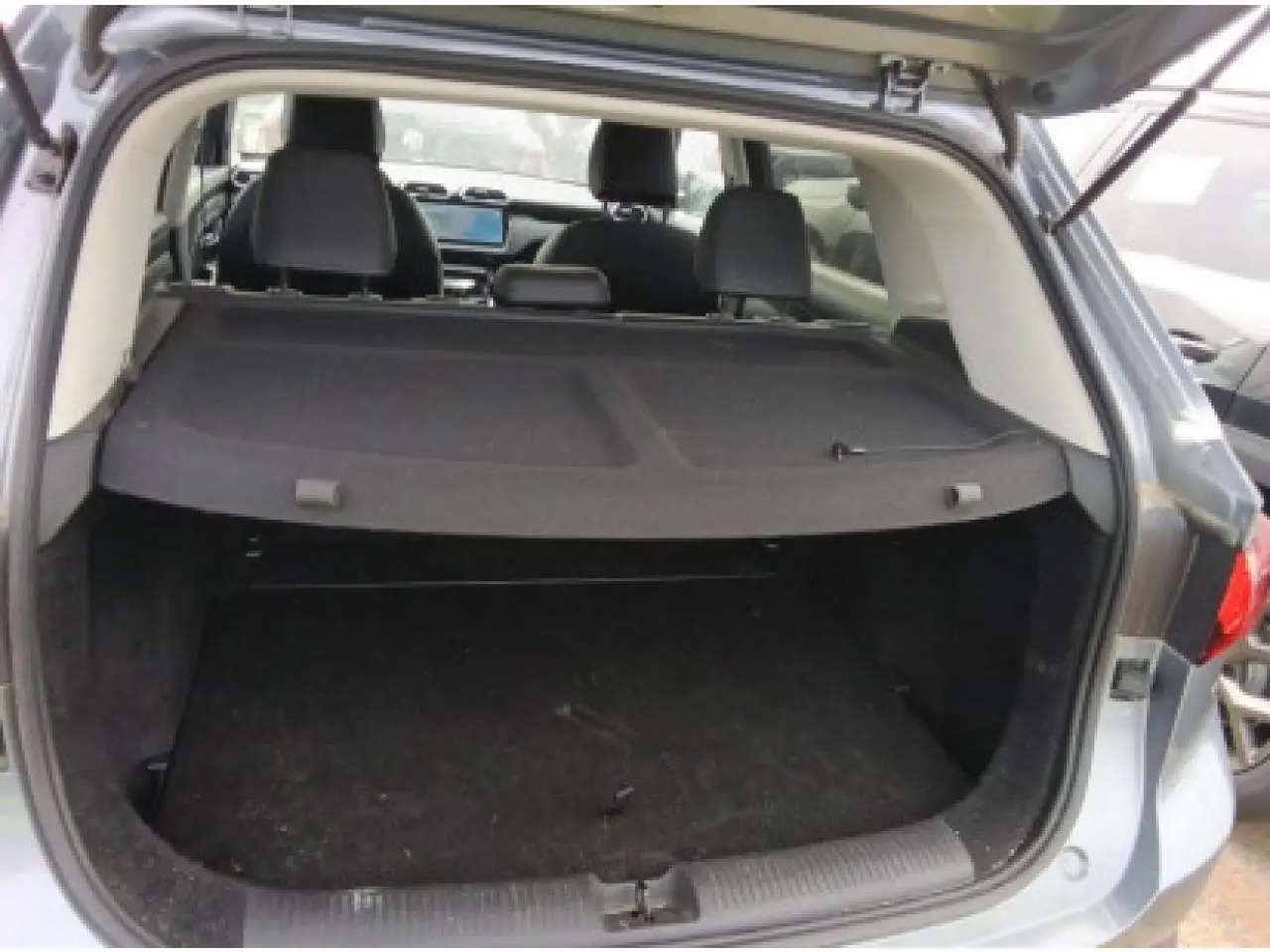 Coffre ouvert vu de l'arrière d'un MG MOTOR ZS 1.5 Hybrid+ 197 Luxury gris Hampstead avec banquette et tableau de bord visibles.