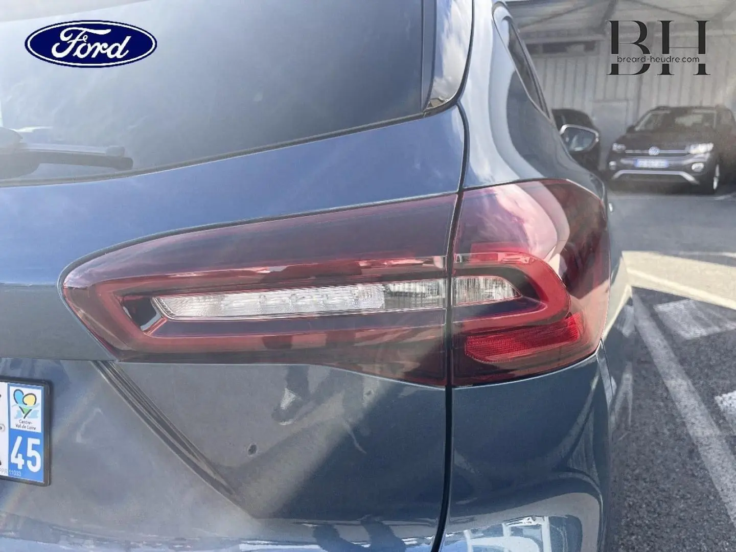 Gros plan sur le feu arrière droit d’une Ford Focus SW 2024 bleu azur métallisé, avec reflet de lumière sur la carrosserie.