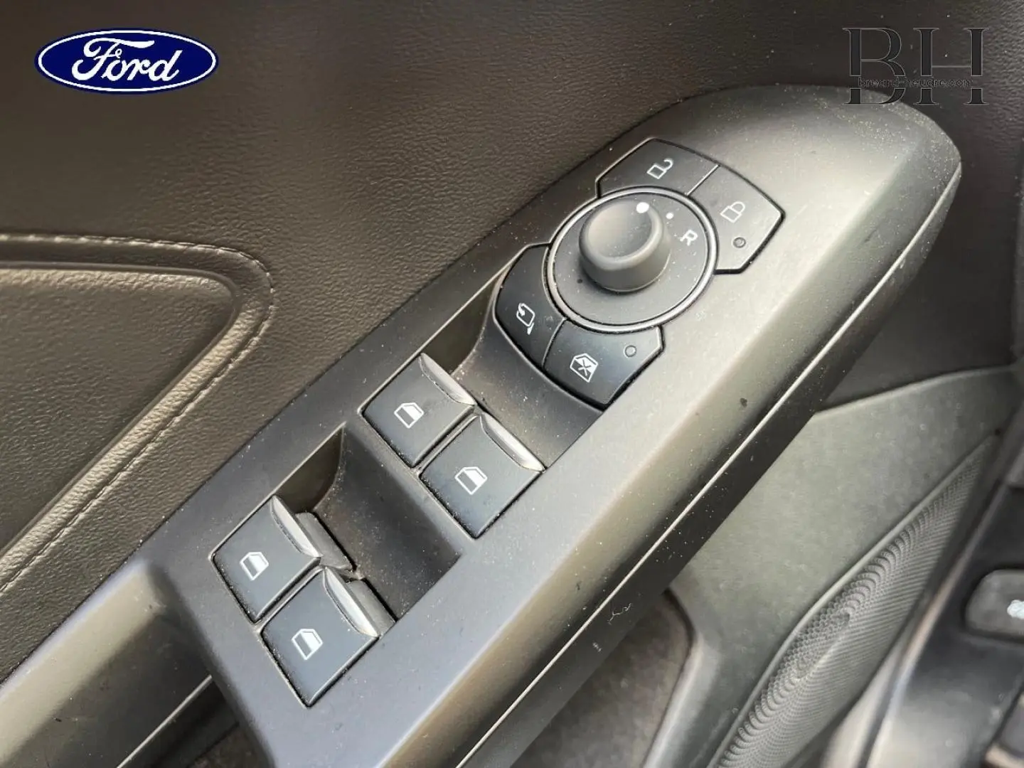 Gros plan sur la commande des vitres et rétroviseurs côté conducteur d'une Ford Focus SW 2024, intérieur noir.