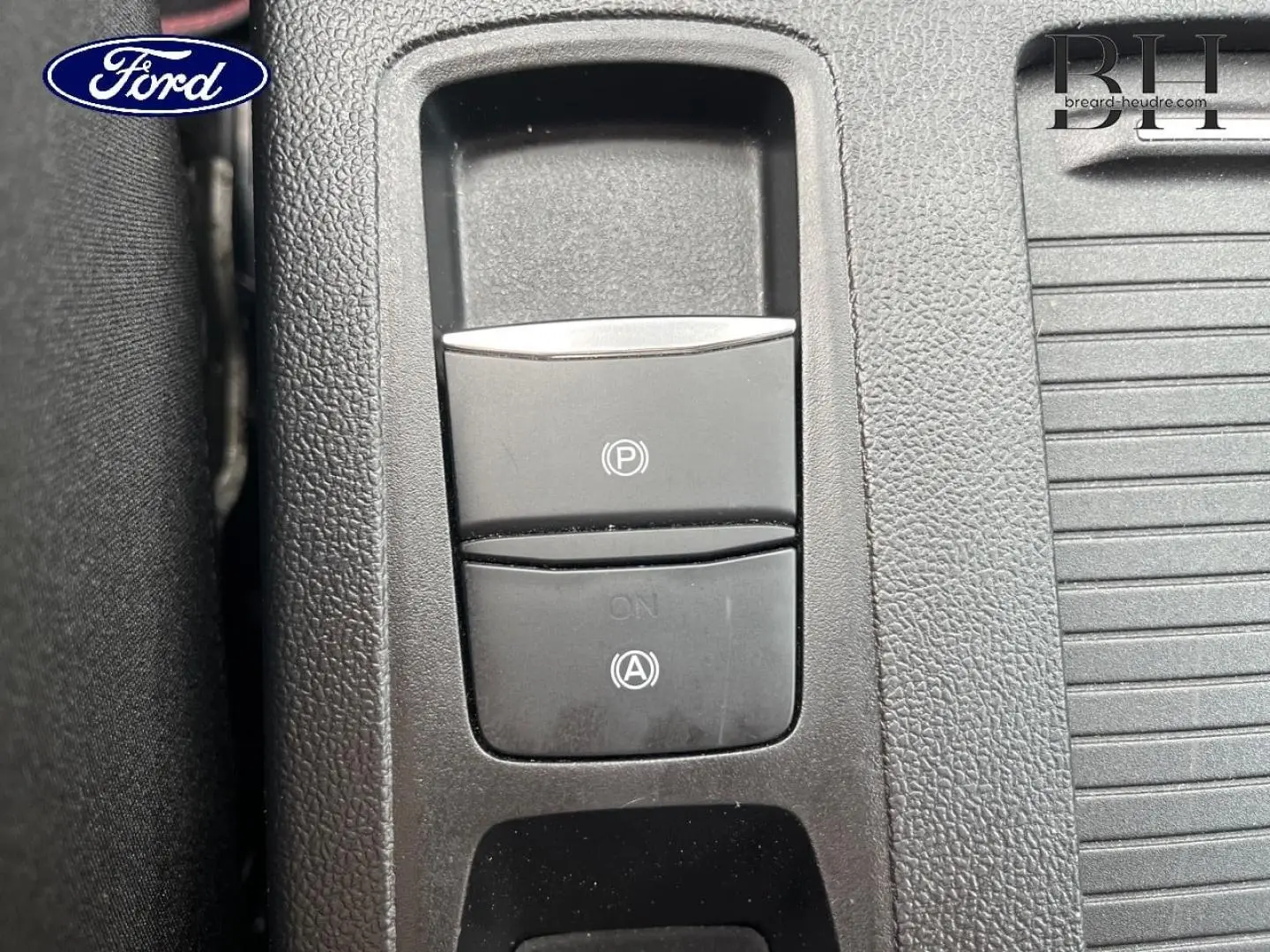Détail du bouton de frein de stationnement électronique et de l'activation du système start-stop sur la console centrale d'une Ford Focus SW 2024.