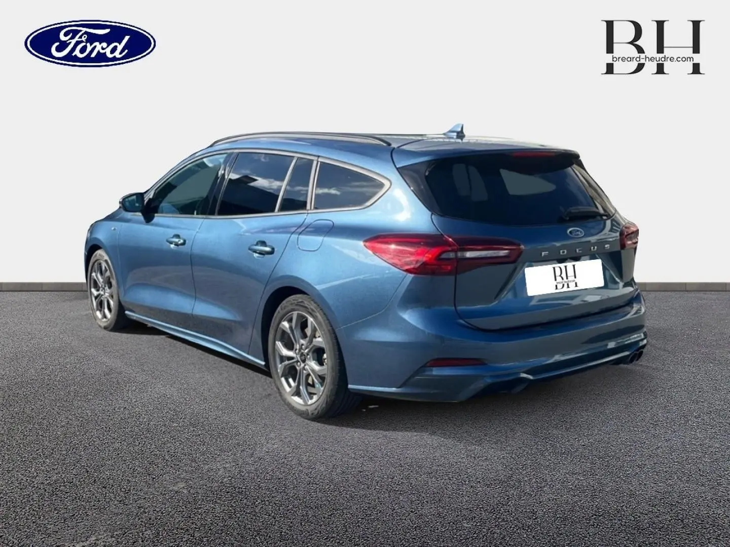 Ford Focus SW bleu azur métallisé vue 3/4 arrière droit, jantes alu et feux arrière LED visibles.