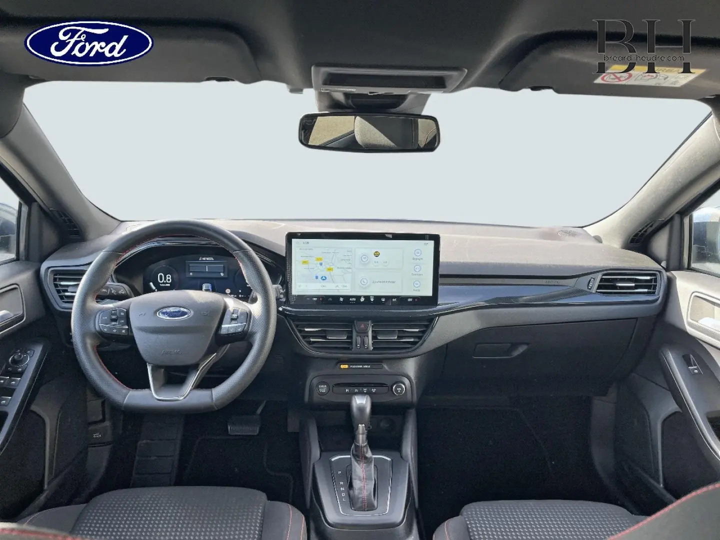 Vue avant de l'habitacle noir de la Ford Focus SW 2024 avec volant cuir, écran tactile central et levier de boîte auto.
