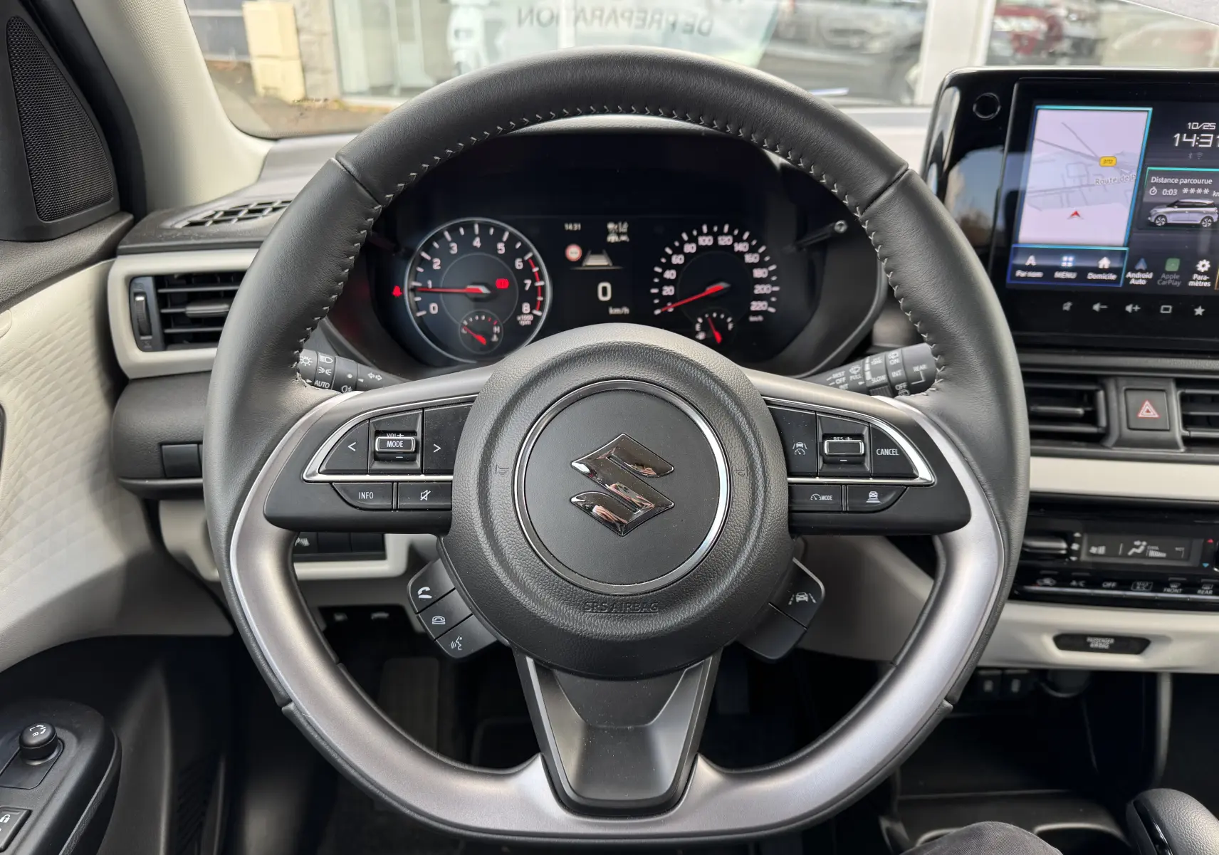 Vue intérieure centrée sur le volant noir de la Suzuki Swift 1.2 Hybrid Privilege, avec tableau de bord et écran tactile visibles.