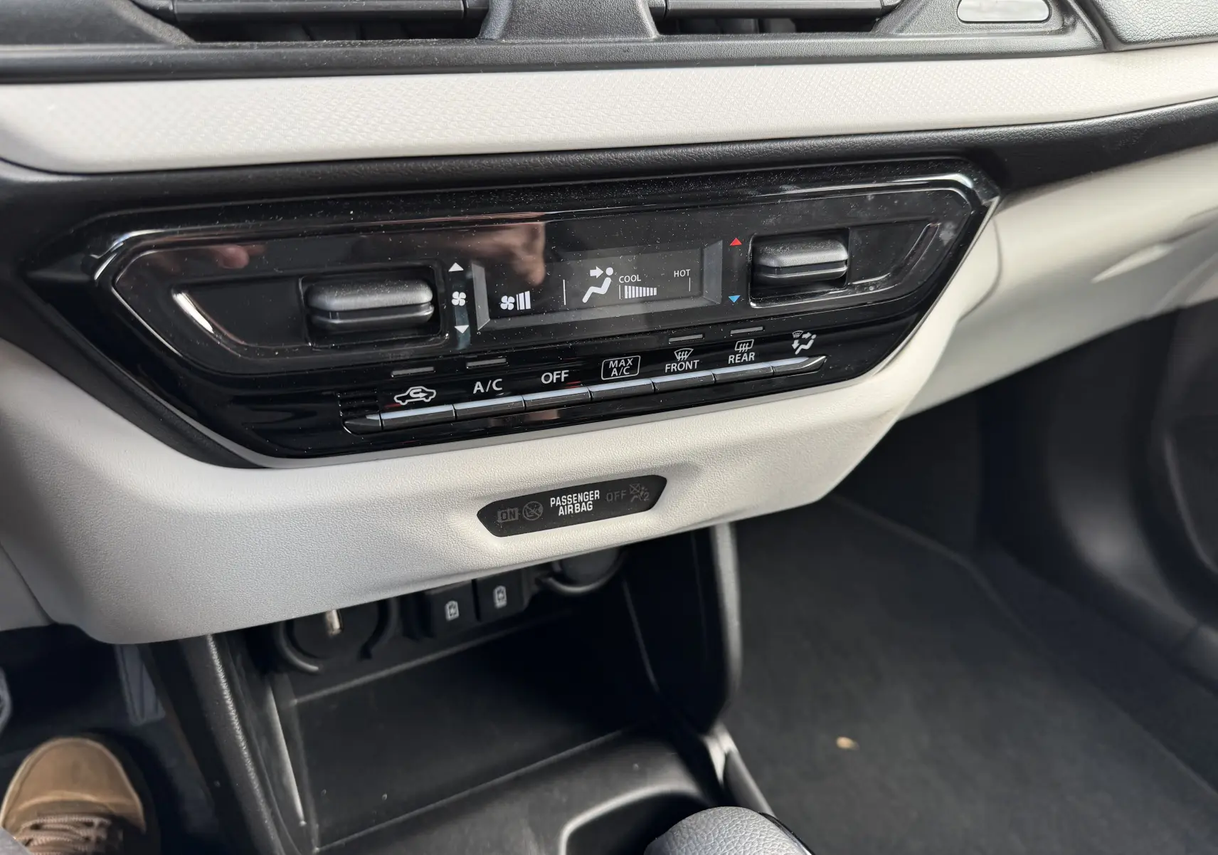Vue rapprochée de la console centrale beige et noire de la Suzuki Swift 1.2 Hybrid Privilege avec commandes climatisation digitales.