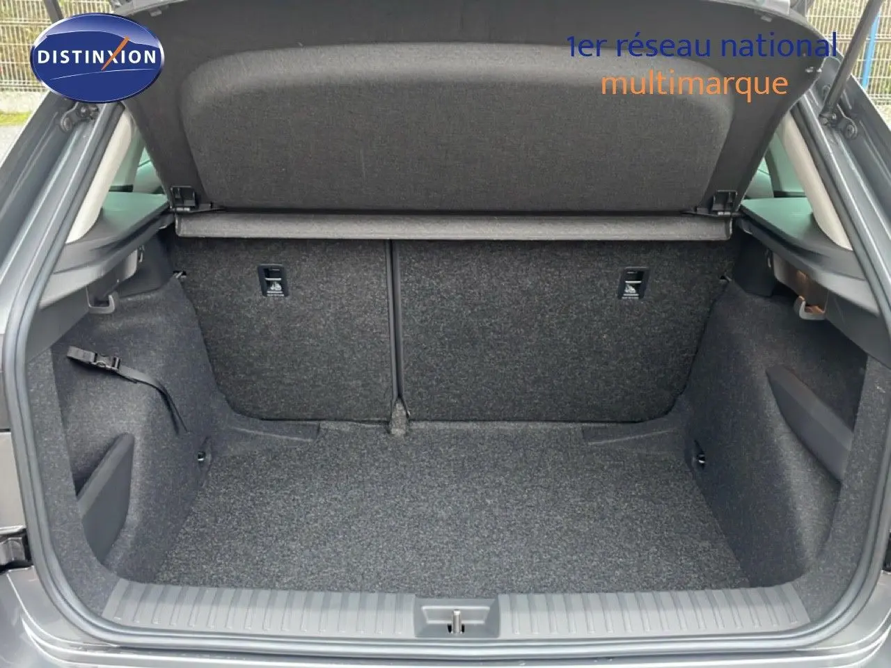 Coffre ouvert du Skoda Kamiq gris graphite métal, vue arrière montrant l'espace de chargement et la moquette intérieure.