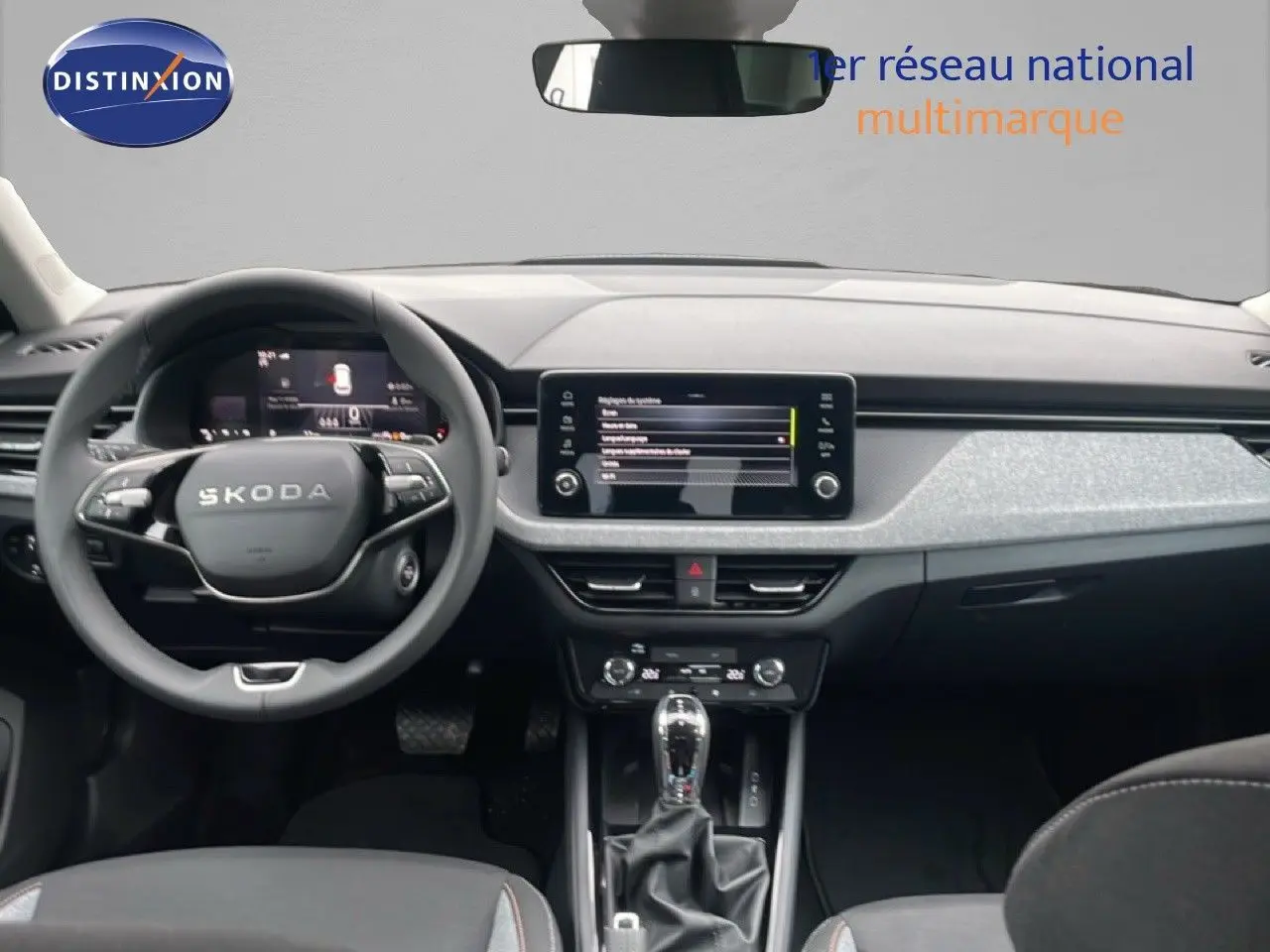 Intérieur moderne du Skoda Kamiq 2025 avec tableau de bord gris clair et écran tactile central visible de face.