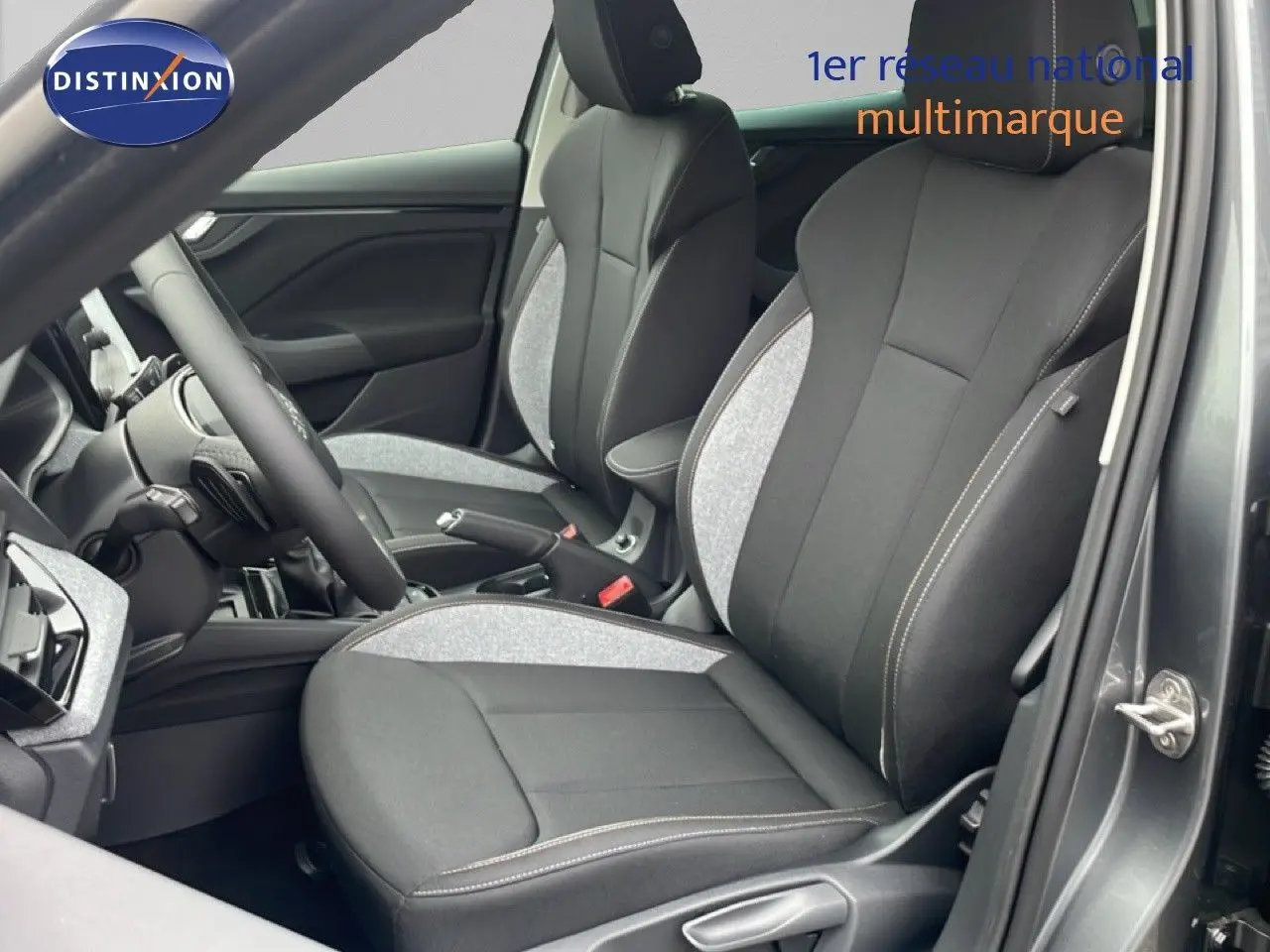 Intérieur du Skoda Kamiq 2025 montrant les sièges avant en tissu noir et gris avec surpiqûres blanches, côté conducteur ouvert.