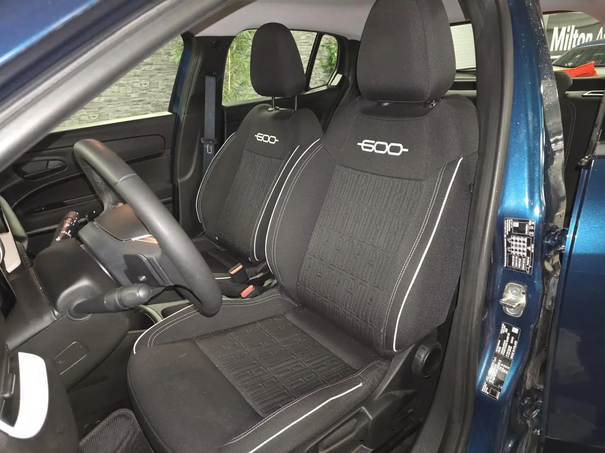 Vue intérieure côté conducteur de la FIAT 600 2024 bleu, sièges tissu noir avec logo "600" brodé blanc.