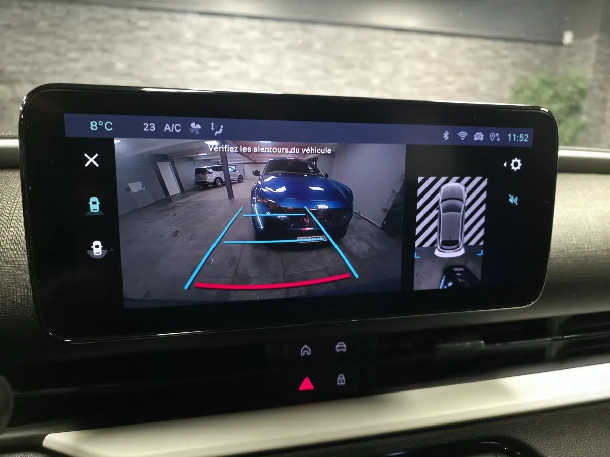 Écran multimédia affichant la caméra de recul et vue 360° d’une FIAT 600 bleu dans un parking intérieur.