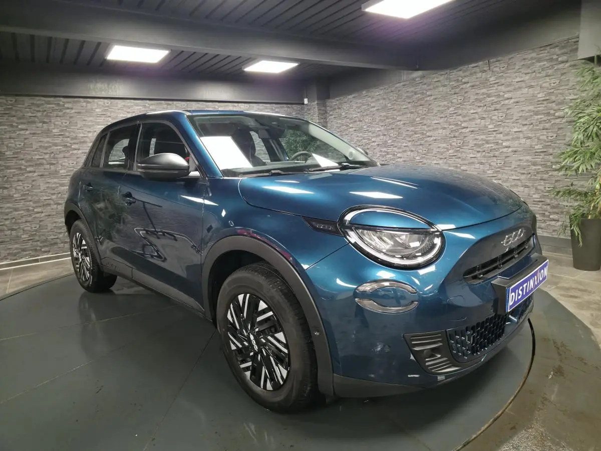 Vue 3/4 avant droit d'une FIAT 600 1.2 Hybrid bleu métallisé avec jantes bicolores et phares LED Infinity.