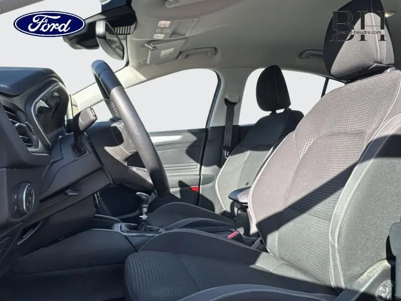 Vue intérieure côté conducteur de la Ford Focus 1.5 EcoBlue 2020 avec sièges tissu noir et volant cuir multifonction.